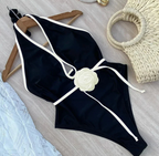 Zwart halter badpak met witte rand en bloemdetail - Bakkermode.nl